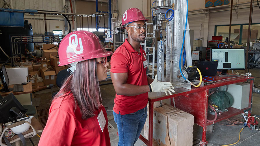 two students wearing hard hats in indoor construction environment